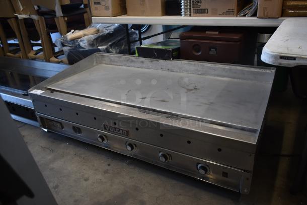 Vulcan commercial griddle with four control knobs, stainless steel surface, showing signs of use, model unidentified.