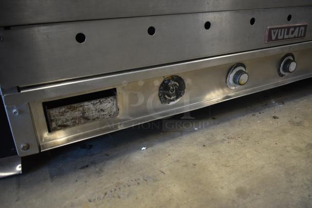 Vulcan commercial countertop griddle with manual knobs. Stainless steel, visible wear. Features control dials and drip tray.