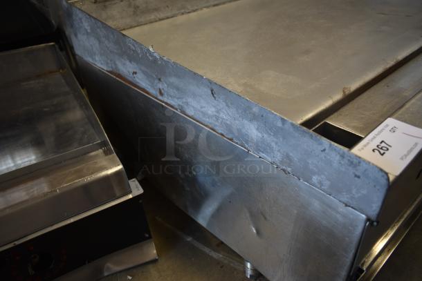 Large industrial griddle showing signs of wear, with metal surface and edges. Auction tag labeled "267 GTY" attached.