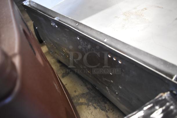 Metal sheet panel with drilled holes, showing some surface rust and wear, indicating use and age, positioned next to a brown object.