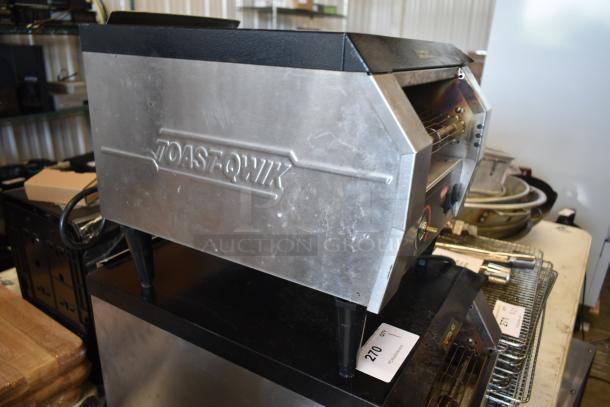 Toaster labeled "TOAST-QWIK," stainless steel body, moderate wear, black plastic feet, auction tag number 270 visible.