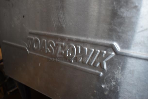 Stainless steel Toast-Qwik toaster with engraved logo. Some surface marks visible, indicating use. Commercial grade.