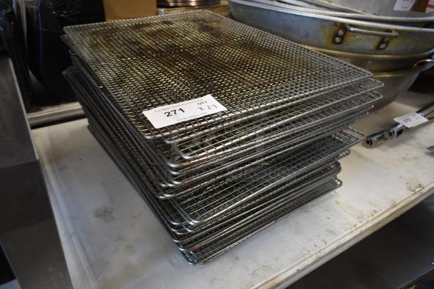 Stack of used metal cooling racks with auction label "271, Qty 27." Racks show signs of use and wear, ideal for kitchen use.