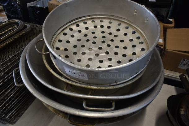 Stack of aluminum industrial kitchen pots and pans, top one perforated for steaming, minor signs of wear, tag reads "273".