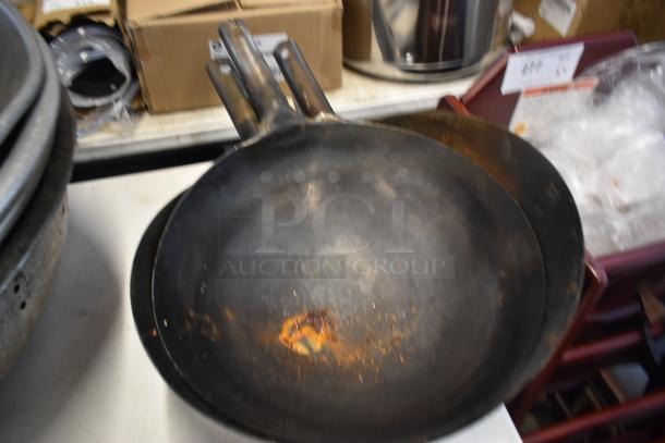 Set of three well-used iron frying pans with visible rust and wear, stacked in a kitchen setting.