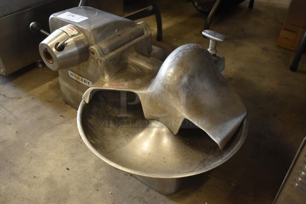 Hobart industrial meat grinder, stainless steel, with lever and safety labels, in used condition. Model details visible.