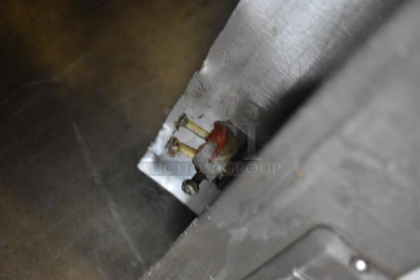 Close-up of a metal component with bolts and red marking, possibly part of industrial machinery. Appears slightly worn.