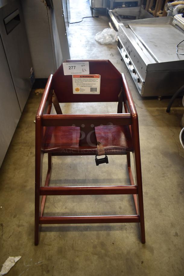 Wooden high chair with dark finish, safety harness included. Good condition with visible warning label and auction tag "277".