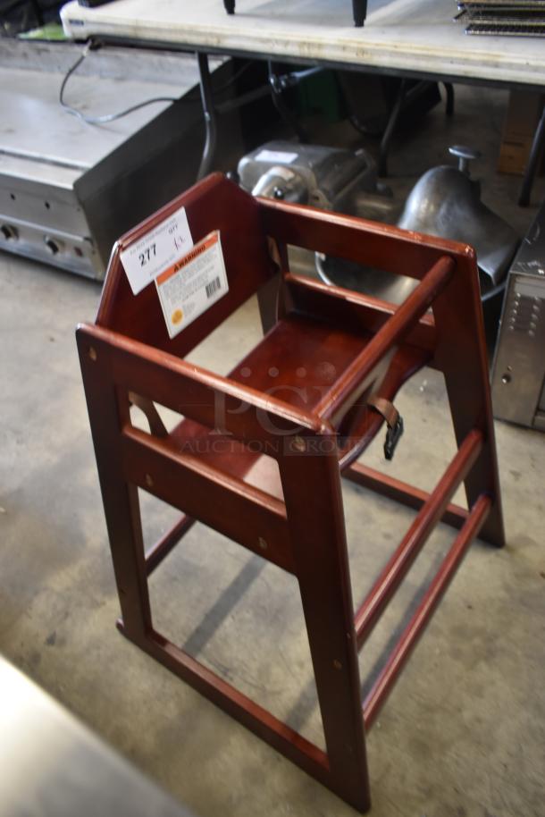 Wooden high chair with a deep brown finish, visible wear, safety strap, and a visible auction lot number tag.