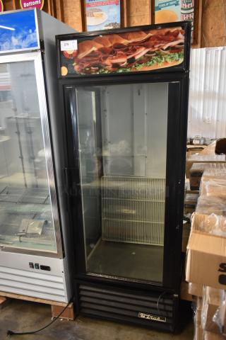 True commercial glass door refrigerator, black, with interior metal shelving, item number 278 tag. Good condition.