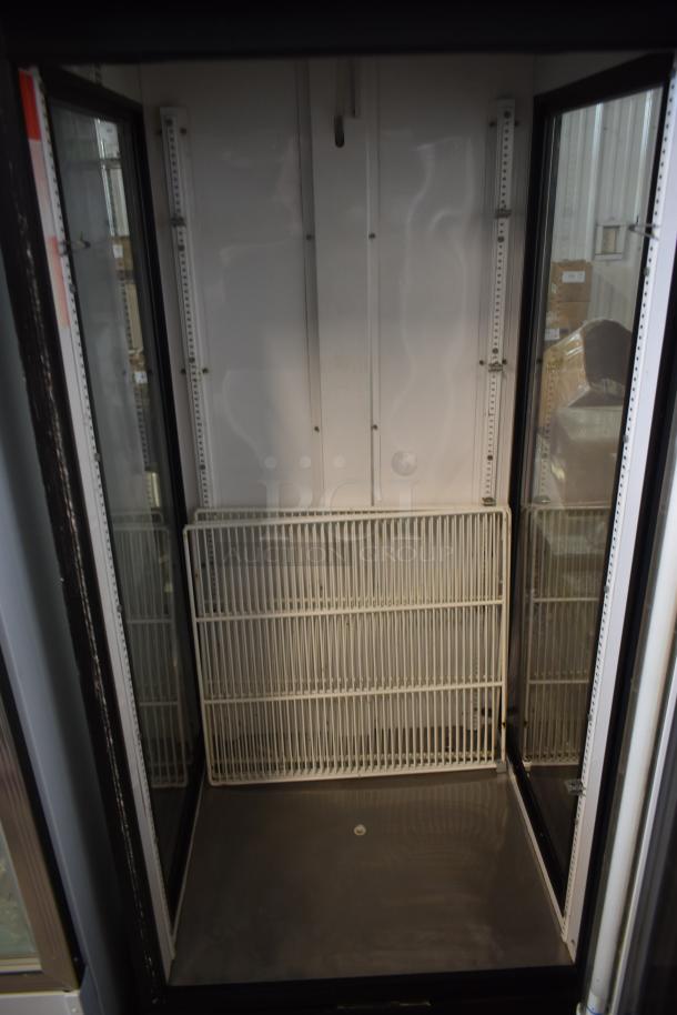 Commercial glass-door refrigerator, empty, white interior, with metal shelving. Clean condition, visible mounting rails.