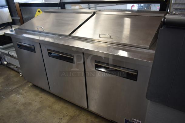 Stainless steel commercial refrigerator with three doors and top sliding lids in good condition, suitable for kitchen use.