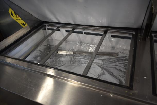 Industrial stainless steel refrigeration unit with open lid, interior lined with reflective material. Appears in used condition.