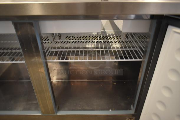 Commercial stainless steel refrigerator with double glass doors, interior wire shelving, and sturdy construction. Used condition.