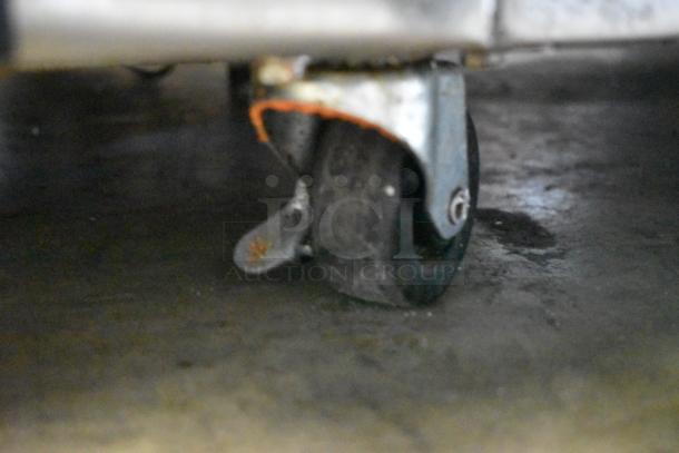 Close-up of a worn caster wheel on a metal frame, showing signs of rust and use, suitable for replacement or repair.