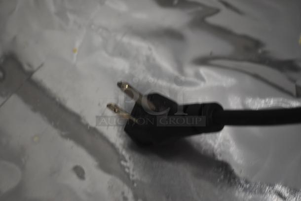Black power cord with two-prong plug, in good condition, set on a reflective surface. No visible labels or markings.