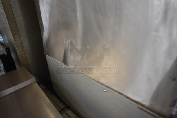 Industrial stainless steel panel with visible dents and screws, reflecting light; used condition.