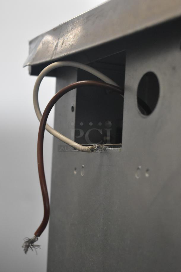 Metal device casing with exposed red and white wires, showing frayed ends. Condition suggests need for repair.