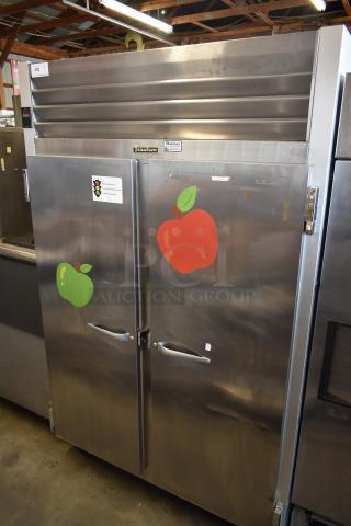 Traulsen commercial refrigerator with dual stainless steel doors, apple decals, and visible manufacturer label. Good condition.
