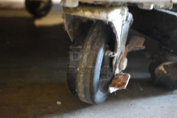 Close-up of a worn caster wheel on a metal frame, showing rust and signs of heavy use.