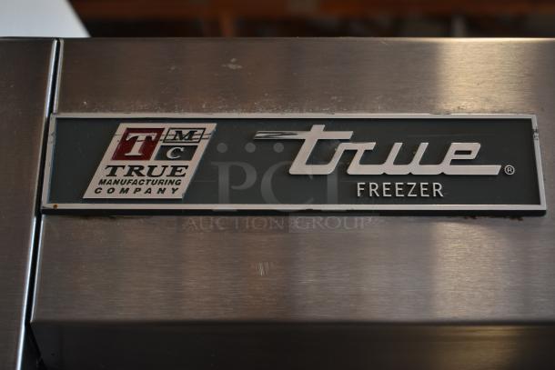 True Manufacturing Company freezer, stainless steel, with visible logo. Slight surface wear, ideal for commercial use.