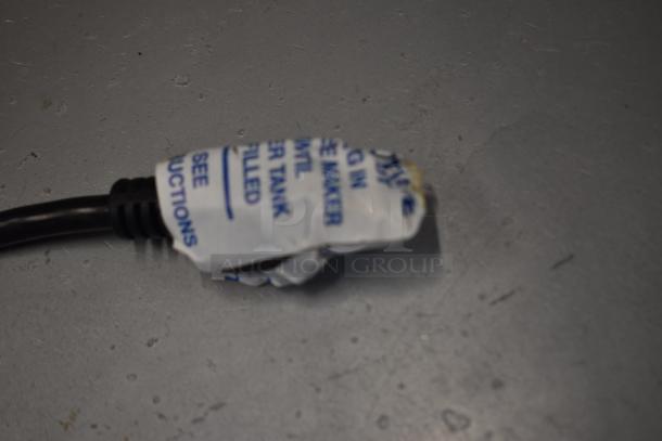 Electrical plug with part of a warning label, wrapped in plastic. Label instructs to see instructions for proper setup.