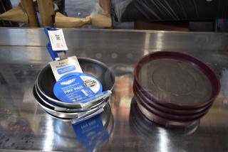 Set of new Vollrath CeramicGuard II fry pans with blue handles and labels, next to stack of maroon trays.
