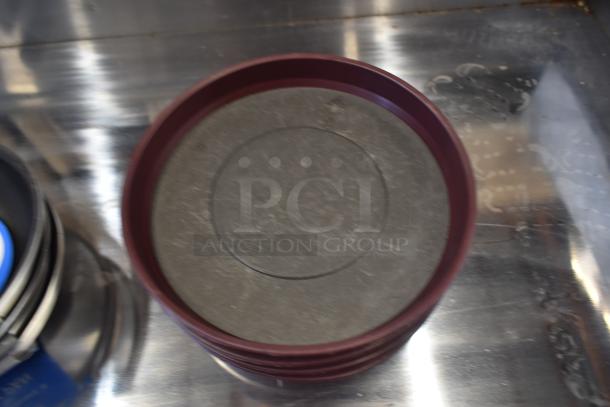 Round maroon-brown tray with textured black surface, slightly worn. Appears on reflective metal surface.