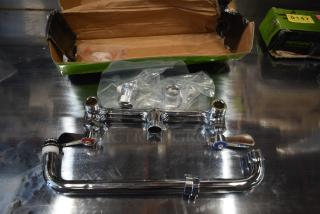 Chrome faucet assembly with hot and cold handles, new in open box, includes installation parts in plastic bags, Regency brand visible.
