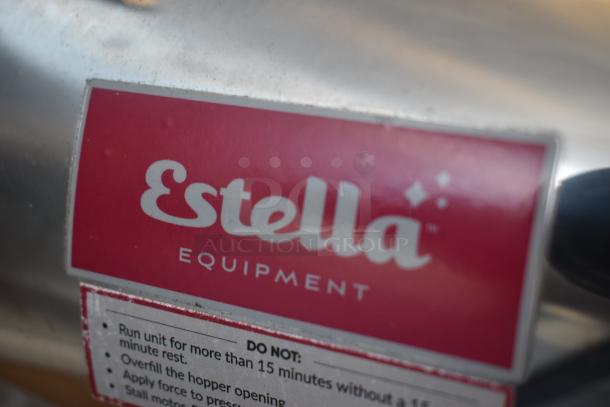 Estella equipment label on metal surface, features cautionary instructions for machine operation.