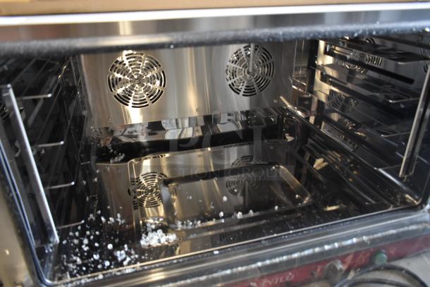Stainless steel convection oven interior with dual fans and multiple racks; in good condition with minimal debris.