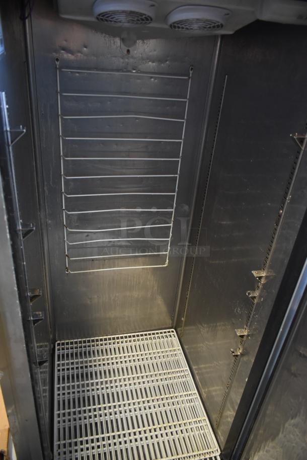 Commercial stainless steel refrigerator interior with wire shelving, showing minor wear. No visible labels or tags.