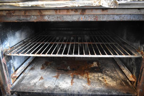 Vintage industrial oven with two wire racks, visible rust, and signs of wear. Ideal for restoration or parts.