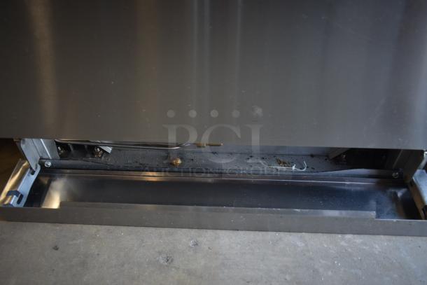Commercial kitchen appliance with stainless steel exterior, internal mechanical components visible, showing signs of use and dust accumulation.