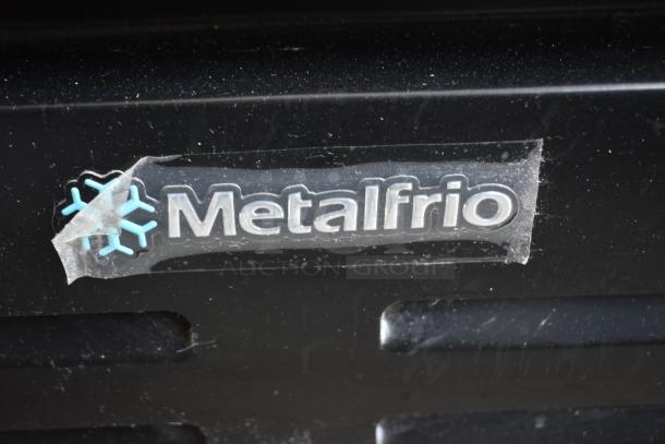 Metalfrio branding on black surface, featuring a snowflake design. Potential cooler or refrigeration equipment.