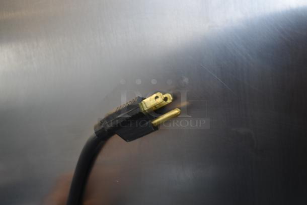 Black power cable with a gold three-prong plug against a metallic surface, appears in good condition.