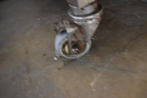 Rusty caster wheel attached to metal furniture leg, showing wear and oxidation, suitable for restoration or parts.