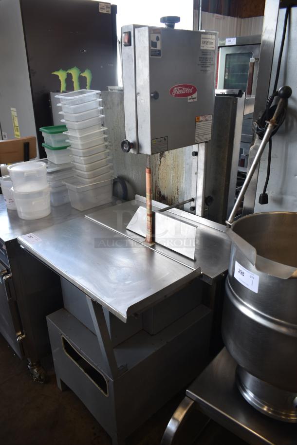 Commercial meat bandsaw, Fleetwood brand, stainless steel, with safety warnings and operational stickers. Used condition.