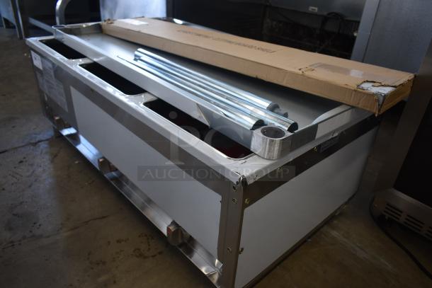 Stainless steel food service counter with metal rails, in used condition; visible manufacturer label and cardboard packaging.