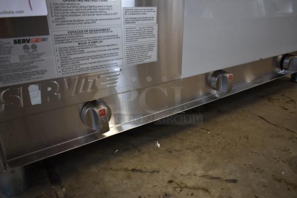 Commercial stainless steel grill with ServIt branding, featuring three control knobs and visible operating instructions.