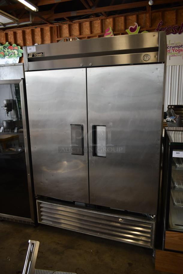 Commercial stainless steel double-door refrigerator, brand "True," with slight dents, visible thermostat gauge, industrial use.
