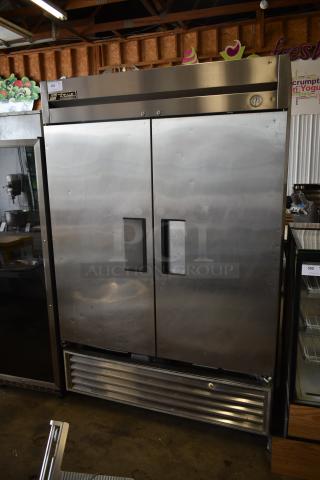 Commercial stainless steel double-door refrigerator, brand "True," with slight dents, visible thermostat gauge, industrial use.