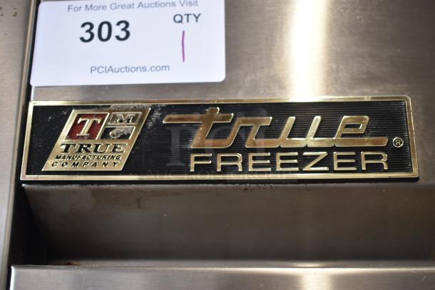 True Freezer label with True Manufacturing Company logo on stainless steel surface, auction tag 303 visible.