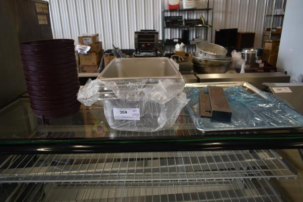 Stack of round baking pans, stainless steel trays, and metal containers on display. Auction tag reads "Lot 304."