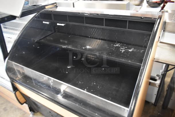 Black refrigerated display case, dual shelves, glass front, visible wear and scratches, suitable for deli or bakery use.