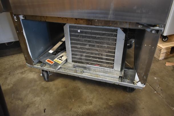 Commercial refrigeration unit on wheels, showing condenser coil. Visible wear and markings, including caution and R-404A labels.