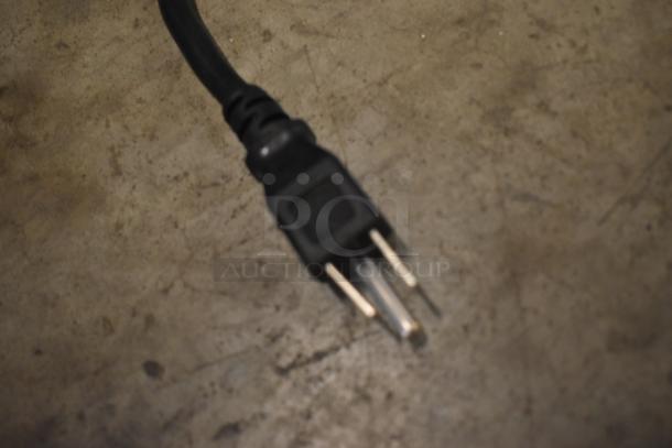 Black power cable plug on a concrete surface, two-prong, showing slight wear, suitable for standard outlets.