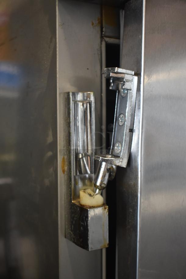 Metallic latch on an industrial appliance, showing signs of wear and rust. No visible markings or labels.