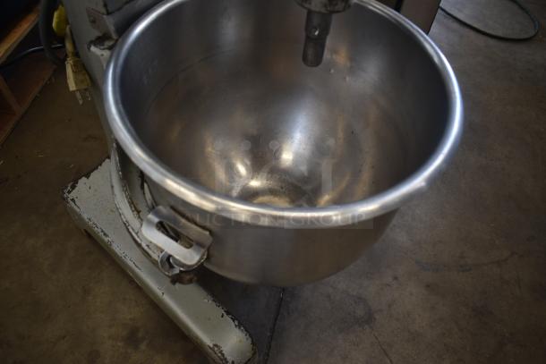 Industrial stainless steel mixer bowl on a stand, showing signs of use with minor scratches. Ideal for commercial kitchens.
