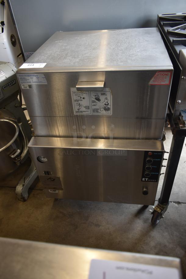 Stainless steel commercial steamer with control panel. ET Series; buttons for start, fill, drain. Visible instructions and caution label.
